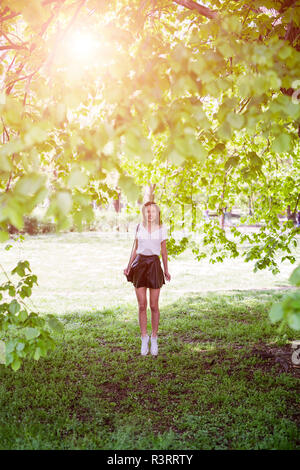 Smiling young woman standing in a park Banque D'Images