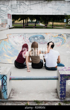 Vue arrière du friends sitting in skatepark Banque D'Images