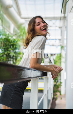 Jeune femme en émissions,leaning on railing, rire, portrait Banque D'Images