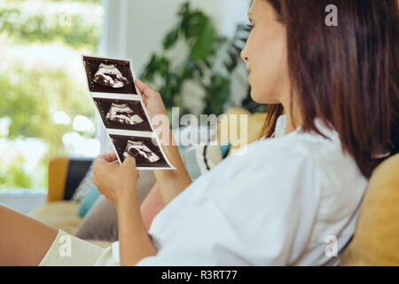 Woman looking at ultrasound photos d'enfant à naître sur la table Banque D'Images