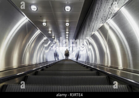 Vue arrière de femme debout sur l'escalier mécanique de la station de métro de Banque D'Images