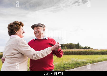 Happy senior couple dancing on country road Banque D'Images