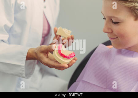 Femme dentiste expliquant un garçon modèle de dent Banque D'Images