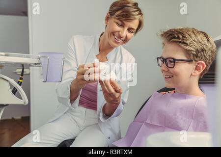 Femme dentiste expliquant un garçon modèle de dent Banque D'Images