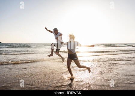 Jeune couple s'amusant à la plage, aux projections d'eau dans la mer Banque D'Images