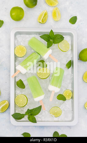 Sucettes glacées à la menthe citron vert, tranches de lime et de feuilles de menthe sur de la glace concassée Banque D'Images