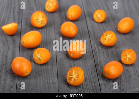 Cumquat kumquat ou avec la moitié sur bllack fond de bois Banque D'Images