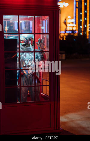 Spaceman debout dans une cabine téléphonique dans la nuit Banque D'Images