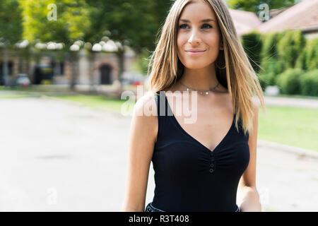 Portrait of smiling teenage girl outdoors looking sideways Banque D'Images