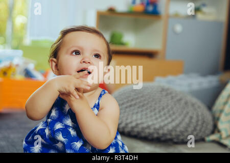 Baby Girl sitting at home looking up Banque D'Images