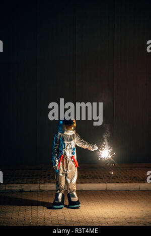 Spaceman debout sur une route de nuit holding sparkler Banque D'Images