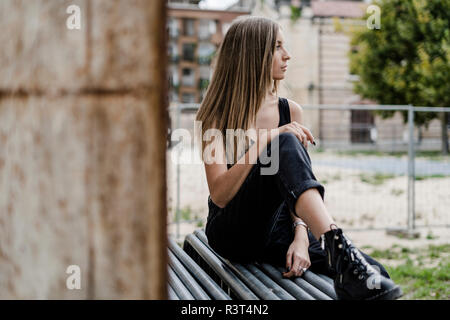 Pensive teenage girl sitting outdoors à autour de Banque D'Images