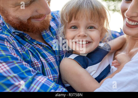 Heureux parents hugging her daughter outdoors Banque D'Images