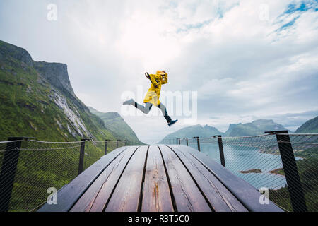 La Norvège, l'île de Senja, homme de sauter sur une plate-forme d'observation sur le littoral Banque D'Images