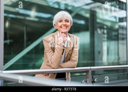 Portrait of smiling senior woman leaning on railing dans la ville Banque D'Images