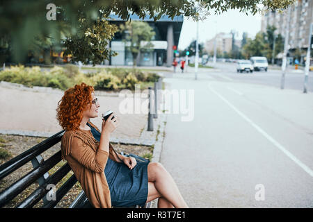 Jeune femme assise sur un banc, de boire du café Banque D'Images