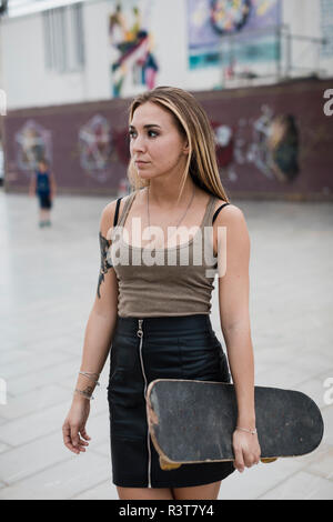 Cool young woman carrying skateboard dans la ville