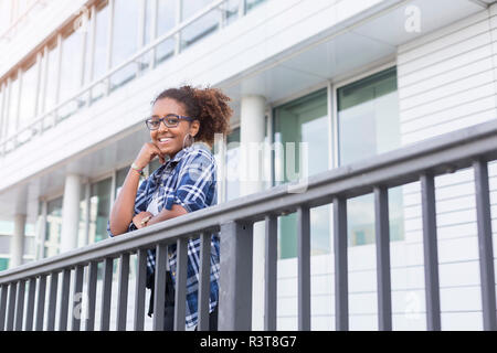 Portrait of smiling young woman leaning on railing Banque D'Images