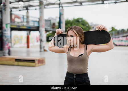 Cool young woman carrying skateboard dans la ville Banque D'Images