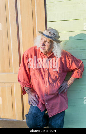 Man avec de longs cheveux gris wearing straw hat looking sideways Banque D'Images