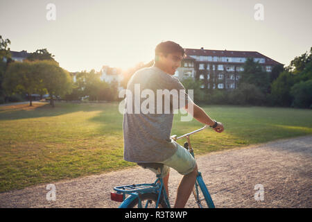 Young man riding bicycle in park Banque D'Images