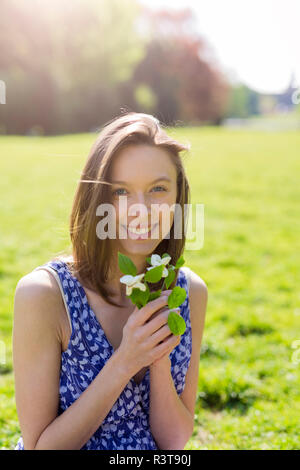 Portrait of smiling young woman in a park holding Flowers Banque D'Images