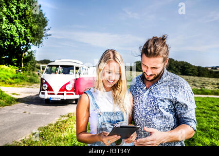 Couple heureux à l'extérieur de van dans paysage rural à la tablette à Banque D'Images