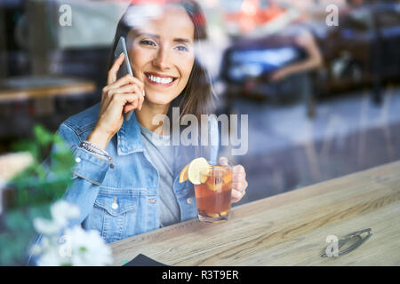 Jeune femme au téléphone à boire le thé dans le café Banque D'Images