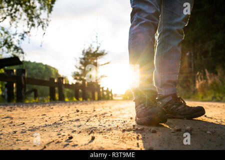 Homme debout dans la rue, au coucher du soleil, low section Banque D'Images