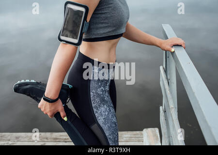 Close-up of young woman stretching athlétique du riverside Banque D'Images