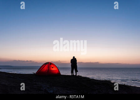 Couple romantique camping sur la plage, embrassant dans Twilight Banque D'Images