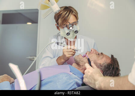 Patient qui traitement dentaire, dentiste à l'aide de fraise dentaire et la tête de loupes et de lumière Banque D'Images