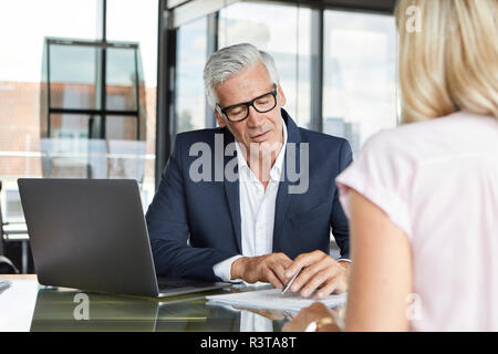 Businessman snd woman sitting in office, discussing project Banque D'Images