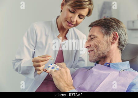 Dentiste expliquant bridge dentaire sur une dent au patient modèle Banque D'Images