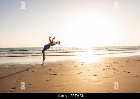 Jeune homme de faire des pirouettes sur la plage Banque D'Images