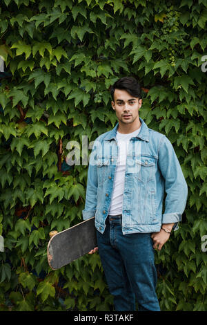 Portrait of young man carrying skateboard Banque D'Images