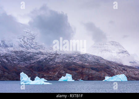 Le Groenland. Au nord-est du parc national du Groenland. Kong Oscar Fjord. Les icebergs et sombre, les nuages bas. Banque D'Images