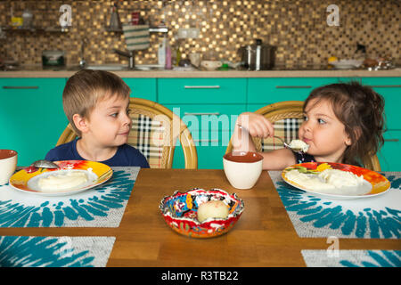 Portrait de garçon et sa petite sœur manger le petit déjeuner dans la cuisine Banque D'Images