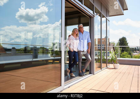 Smiling mature couple standing at toit-terrasse à la maison Banque D'Images