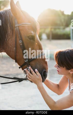 Smiling woman stroking horse Banque D'Images