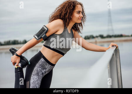 Jeune femme sportive qui s'étend du riverside Banque D'Images