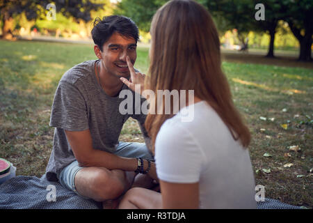 Jeune couple assis dans un parc, s'amuser Banque D'Images