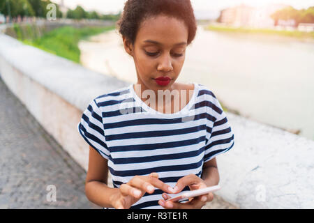 Jeune femme au bord du fleuve using cell phone Banque D'Images