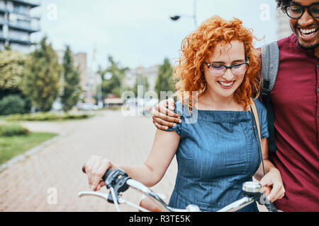 Amis marchant en parc, parlant, woman pushing bicycle Banque D'Images