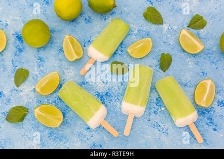 Sucettes glacées à la menthe citron vert, des limes et des feuilles de menthe sur fond bleu clair Banque D'Images