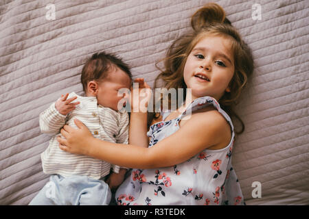 Smiling girl lying on blanket de câlins avec son petit frère Banque D'Images
