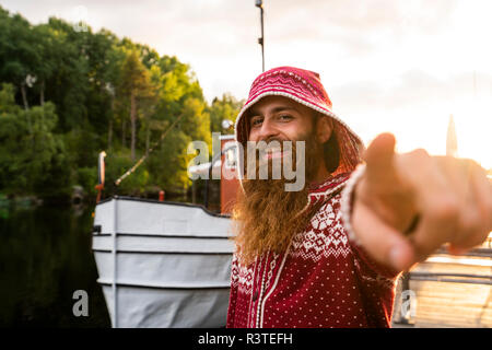 La Finlande, Kajaani, joyeux jeune homme. Le port de veste, houded standing on Jetty, faire les gestes de la main Banque D'Images