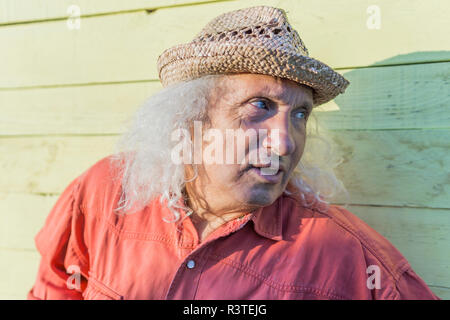 Man avec de longs cheveux gris wearing straw hat looking sideways Banque D'Images