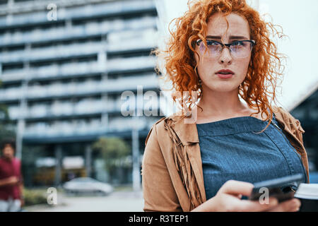 Jeune femme marche dans la ville, using smartphone Banque D'Images