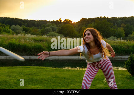 Young woman throwing flying disc Banque D'Images